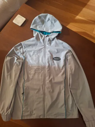 Cortavientos JD Sports Gris y Turquesa.