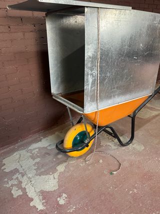 Carretilla de obra naranja con panel metálico