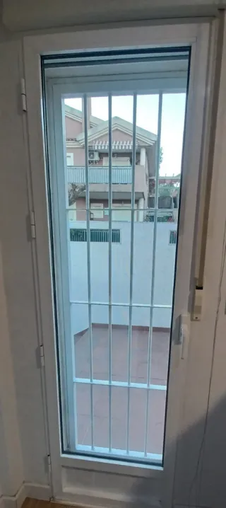Puerta aluminio balconada con reja.