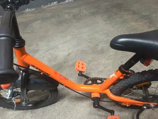 Bicicleta infantil naranja con ruedines