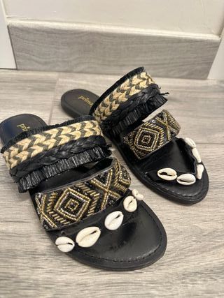 ciabatte nere con conchiglie e pietre