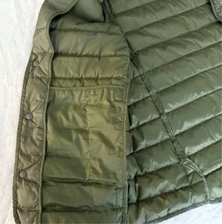 Chaleco Uniqlo de plumas verde abotonado.