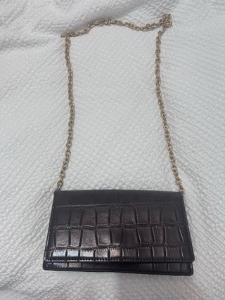 Bolso de mano marrón con cadena dorada.