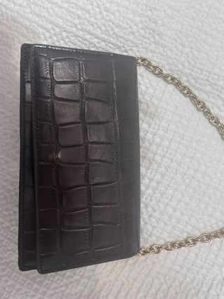 Bolso de mano marrón con cadena dorada.