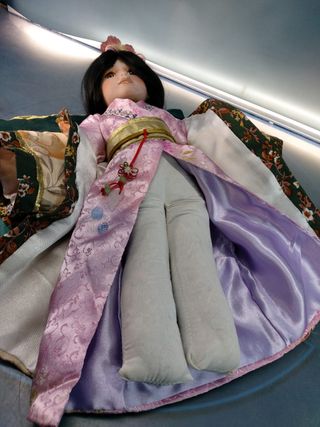 Hana. Bambola di porcellana seduta su cuscino. Abito giapponese, Kimono.