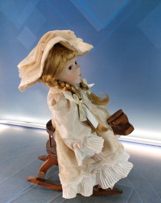 Esther. Bambola di porcellana seduta su un'altalena, cavallo di legno.