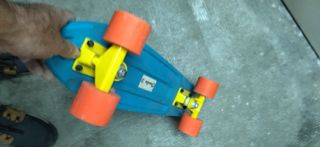 Monopatín azul con ruedas naranjas