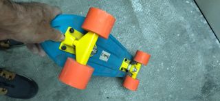 Monopatín azul con ruedas naranjas