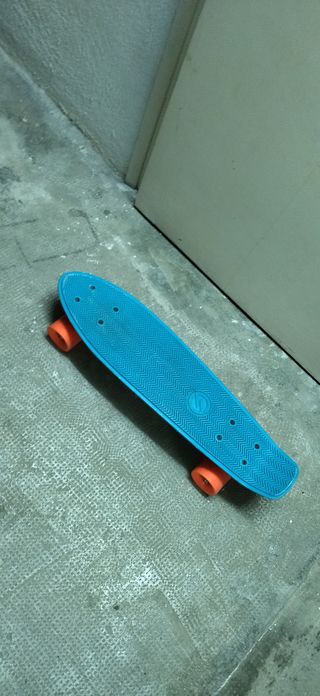 Monopatín azul con ruedas naranjas