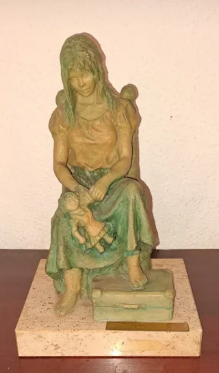 Figura de niña con muñeca y maleta.