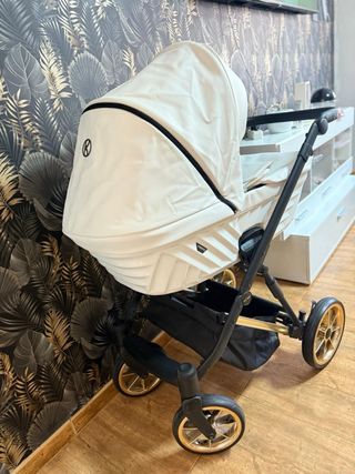 Carrito de bebé blanco con detalles negros dorados