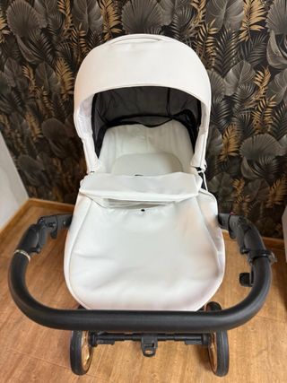 Carrito de bebé blanco con detalles negros dorados