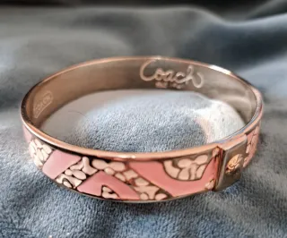 Pulsera Coach dorada y rosa, o plateado y rosa.