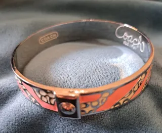 Pulsera Coach dorada y rosa, o plateado y rosa.