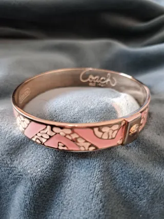 Pulsera Coach dorada y rosa, o plateado y rosa.