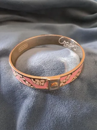 Pulsera Coach dorada y rosa, o plateado y rosa.