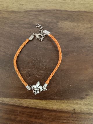 Pulsera de color naranja con avalorio plateado.