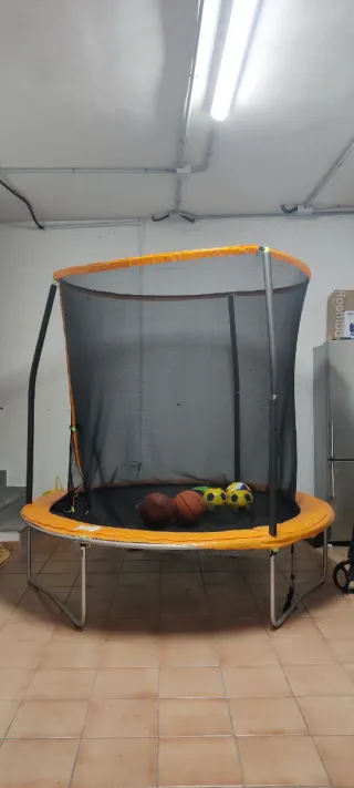 Cama elástica naranja con red de seguridad