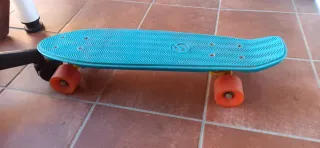 Monopatín azul con ruedas naranjas