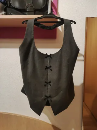 Chaleco Zara gris con lazos negros.