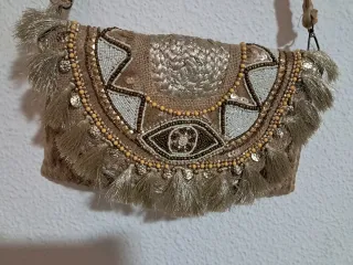 Bolso de mano dorado con flecos
