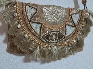 Bolso de mano dorado con flecos