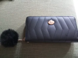 Cartera de mano negra con pompón