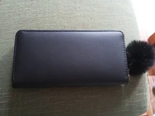 Cartera de mano negra con pompón