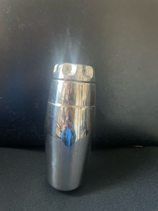 Coctelera de metal plateado con recetario.