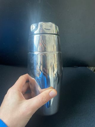 Coctelera de metal plateado con recetario.