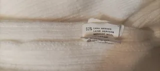 Jersey blanco de lana, con cuello alto con botón.