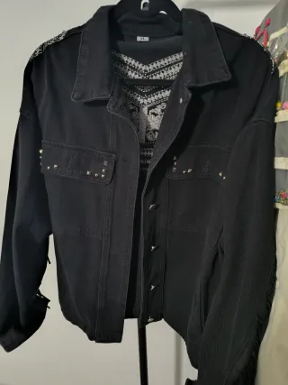Chaqueta tejana negra con flecos y tachuelas.