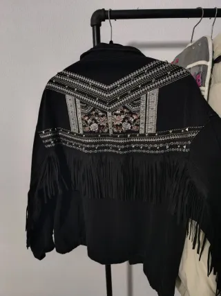 Chaqueta tejana negra con flecos y tachuelas.