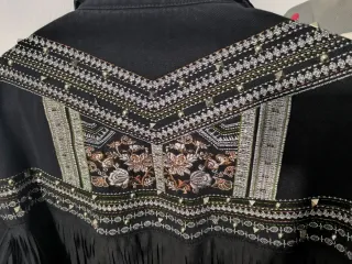 Chaqueta tejana negra con flecos y tachuelas.