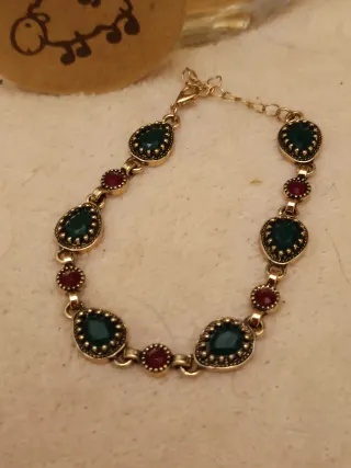 Pulsera dorada con piedras verdes y rojas