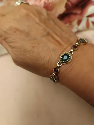 Pulsera dorada con piedras verdes y rojas