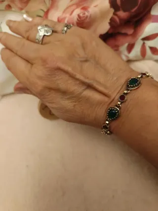 Pulsera dorada con piedras verdes y rojas