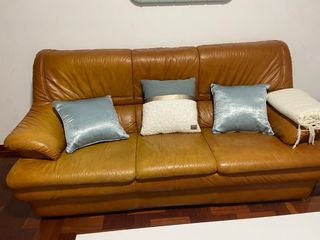 Sofá de piel marrón con alguna pequeña mancha
