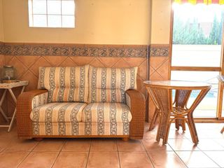 Sofá y mesa de mimbre con tapa de cristal