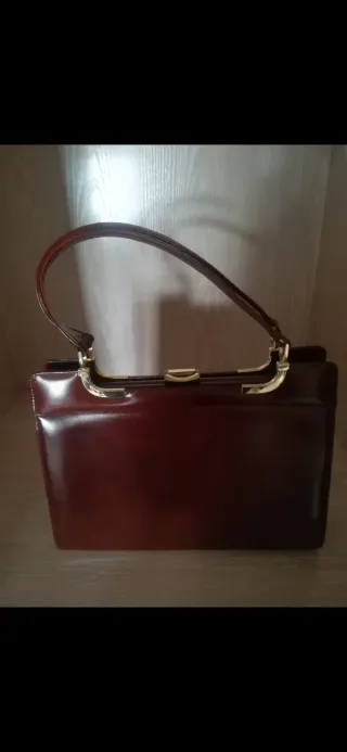 Bolso piel marrón dos asas y boquilla dorada.