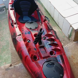 Kayak rojo y negro con chaleco y remo