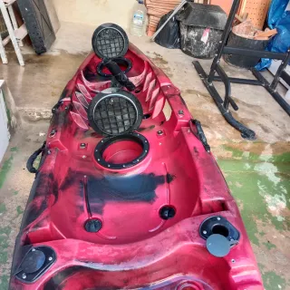 Kayak rojo y negro con chaleco y remo