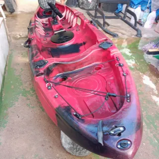 Kayak rojo y negro con chaleco y remo