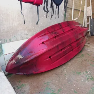 Kayak rojo y negro con chaleco y remo