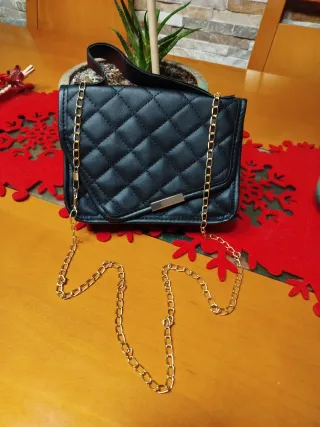 Bolso negro con cadena dorada.