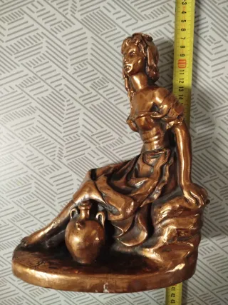 Escultura de mujer sentada con cántaro, en bronce.