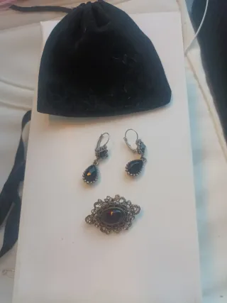 Pendientes y broche plateados con detalles negros