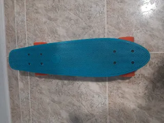 Monopatín azul con ruedas naranjas