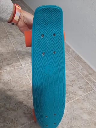 Monopatín azul con ruedas naranjas