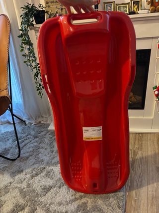 Trineo rojo con freno de mano, pago en mano.